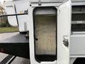 A white 2008 Ford F-550 service truck with an open utility compartment door revealing an empty interior space