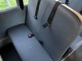 A gray bus seat with seatbelts and a safety buckle visible