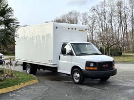 A 2015 GMC Savana delivery truck with a large white cargo box is parked with its front wheels turned sharply to the left