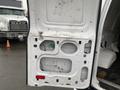 A 2011 Ford Econoline van with an open rear door displaying the interior framework and paneling