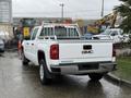 A white 2015 GMC Sierra 1500 pickup truck with a ladder rack in the bed and chrome accents on the rear bumper.