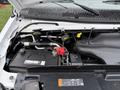 The engine compartment of a 2019 Ford Econoline showing the engine, battery, and various fluid reservoirs