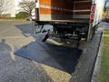 A 2020 Isuzu NPR truck with a lowered hydraulic lift gate in the rear position ready for loading or unloading items