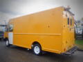 A yellow 2008 Freightliner MT45 Chassis with a boxy design and rear doors, featuring white wheels and a light bar on the roof