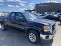 A 2014 GMC Sierra 1500 in black with a spacious cab and cargo bed parked at a lot showcasing its modern truck design and chrome accents