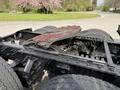 Close-up of a 2012 Volvo VNL tractor-trailer fifth wheel with red paint detailing surrounded by heavy-duty tires and metal components
