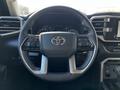 Steering wheel of a 2023 Toyota Tundra featuring the Toyota logo with various control buttons on the spokes