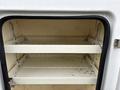 Interior view of a storage compartment in a 2018 Ford F-550 with two white shelves and no items inside