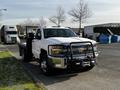 A 2017 Chevrolet Silverado 3500HD with a flatbed and a front grille guard parked in an industrial area