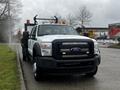 A 2015 Ford F-550 truck in white with a black front grille and orange warning lights on the roof