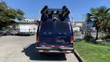 A blue 2013 Ford Econoline van with a rooftop sound speaker system and a red and white reflective stripe