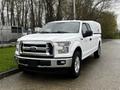 A white 2017 Ford F-150 with a silver grille and a truck bed cover parked on a street