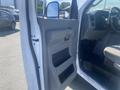 A 2009 Ford Econoline with an open driver side door revealing a grey interior and dashboard with controls and a driver's seat visible