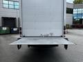 A 2018 Isuzu NPR box truck with a lowered liftgate at the rear