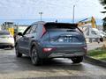 A blue 2023 Kia Niro EV with a sleek design and distinctive rear lights is parked, showcasing its modern styling and eco-friendly features