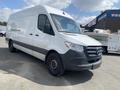 A 2024 Mercedes-Benz Sprinter van in white with a gray lower front bumper and black wheels parked at an outdoor location
