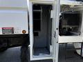A partially open storage compartment on a 2006 GMC C7C00 showcasing empty shelves and a part of the vehicle's internal components