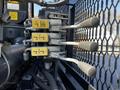 A close-up of four hydraulic control levers in yellow and metal, attached to a 2012 Freightliner M2 112 truck, mounted in a black metal frame with a mesh design
