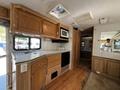 Interior of a 2000 Ford Motorhome featuring wooden cabinets a kitchenette with a sink microwave and refrigerator and a mirror on the wall