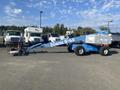 A blue 1997 Genie S-65 4X4 aerial lift with a long arm and a basket at the end positioned on large wheels