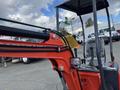 A red 2024 AGT Mini Excavator with a small bucket arm and control levers in the operator's cabin