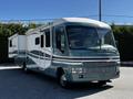 A 2000 Ford Motorhome in a teal and gray color with a slide-out extension on the side and a prominent front grille design