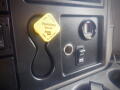 Close-up of the dashboard controls in a 2016 International WorkStar 7500 featuring a yellow parking brake lever a gauge and a key ignition switch
