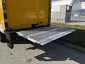 A silver loading ramp extended from the back of a yellow 2017 Hino 155 truck