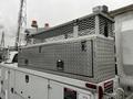 A metal tool storage box with a diamond plate finish mounted on top of a white truck with safety lights