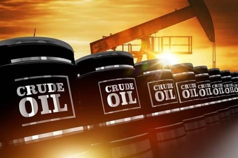 A row of black barrels labeled crude oil with an oil pump jack in the background against a sunset sky