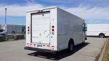 A 2011 Ford Econoline cargo van with a white exterior and a blank rear door parked in a lot