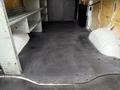 A 2014 GMC Savana empty cargo van interior featuring a rubberized floor and metal shelves on one side