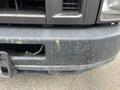 A 2010 Ford Econoline with a weathered and rusty front bumper displaying various marks and surface imperfections