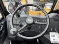 The interior of a 2014 Caterpillar TL1055C featuring a steering wheel with a CAT logo control knobs and a mounted fan