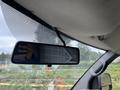 A 2014 GMC Savana's rearview mirror mounted on the windshield with part of the dashboard and a hand visible in the reflection