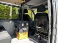 Interior of a 2017 Mercedes-Benz Sprinter showing two front seats a box on the floor and a bench seat in the back