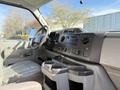 Interior view of a 2012 Ford Econoline E-450 showing the dashboard steering wheel and center console with cup holders