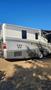 A 2007 Winnebago Adventure motorhome with a gray exterior and slide-out feature parked on grass