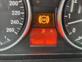 Dashboard of a 2011 BMW 3-Series displaying warning lights including ABS and parking indicators along with mileage and trip information