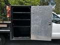 A 2016 Ford F-550 with an open tool compartment featuring metal shelves inside
