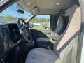 Interior of a 2012 GMC Savana showing two driver seats and dashboard with basic controls and a mirror