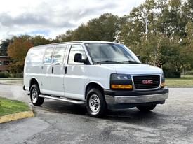 2023 GMC Savana van with a white exterior and black grille parked on a roadway
