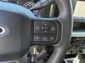 A close-up of the steering wheel controls of a 2024 Ford F-550 featuring buttons for menu navigation back options and phone connectivity