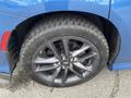 A close-up view of a blue 2022 Dodge Charger's wheel featuring a multi-spoke alloy rim and a black tire with visible tread pattern