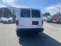 A white 2009 Ford Econoline van is parked with its rear facing the viewer displaying a blank license plate holder