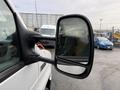 A 2022 Ford E-450 with a side mirror reflecting its surroundings and showing droplets of water on its surface