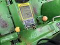 Close-up of a control panel on a 2003 John Deere 790 tractor featuring levers knobs and caution labels in bright yellow and black