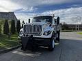 A white 2011 International 7500 truck with a large front grille and mounted plow attachment facing forward