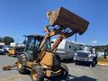 A 2008 Case Super 580M backhoe loader with a raised front bucket and a yellow and orange color scheme