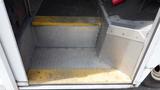 A 2011 Ford Econoline with yellow steps leading to the entrance and a metal interior floor featuring a diamond pattern